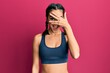 © Krakenimages.com - Young brunette girl wearing sportswear and braids peeking in shock covering face and eyes with hand, looking through fingers with embarrassed expression.
