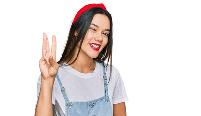 Poster - Young hispanic girl wearing casual clothes showing and pointing up with fingers number three while smiling confident and happy.