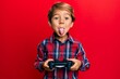 © Krakenimages.com - Adorable latin kid playing video game holding controller sticking tongue out happy with funny expression.