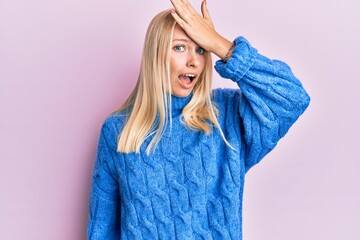 Canvas Print - Young blonde girl wearing wool winter sweater surprised with hand on head for mistake, remember error. forgot, bad memory concept.