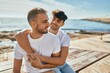 © Krakenimages.com - Young gay couple smiling happy sitting on the bench at the beach promenade.