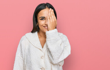 Wall Mural - Young brunette woman wearing casual clothes covering one eye with hand, confident smile on face and surprise emotion.