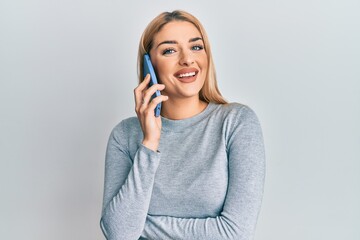 Young caucasian woman having conversation talking on the smartphone looking positive and happy standing and smiling with a confident smile showing teeth