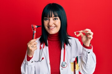 Poster - Young hispanic doctor woman holding deafness headset and otoscope smiling with a happy and cool smile on face. showing teeth.