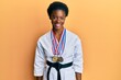 Young african american girl wearing karate kimono and black belt looking positive and happy standing and smiling with a confident smile showing teeth