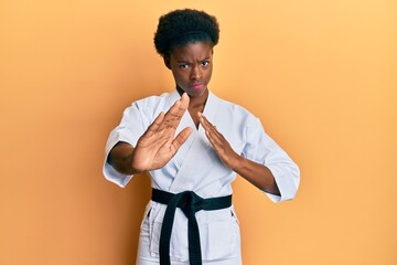 Canvas Print - Young african american girl wearing karate kimono and black belt skeptic and nervous, frowning upset because of problem. negative person.