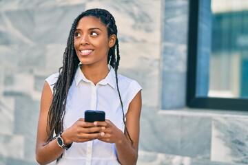 Poster - Young african american woman smiling happy using smartphone at the city.