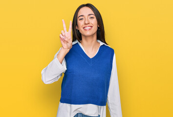 Young hispanic girl wearing casual clothes showing and pointing up with fingers number two while smiling confident and happy.