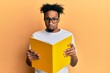 © Krakenimages.com - Young african american man with beard reading a book wearing glasses skeptic and nervous, frowning upset because of problem. negative person.