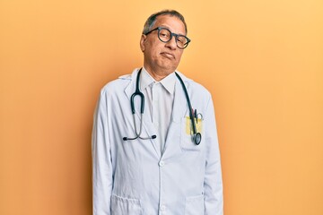 Poster - Middle age indian man wearing doctor coat and stethoscope depressed and worry for distress, crying angry and afraid. sad expression.