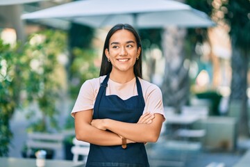 Poster - Young latin barista girl with arms crossed smiling happy at the coffee shop