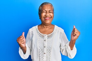 Poster - Senior african american woman wearing casual clothes celebrating surprised and amazed for success with arms raised and eyes closed