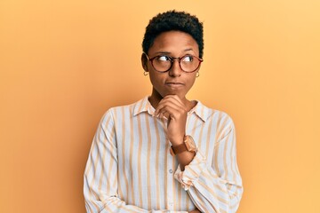 Wall Mural - Young african american girl wearing casual clothes and glasses thinking concentrated about doubt with finger on chin and looking up wondering