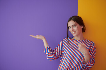 Portrait of happy smiling young beautiful woman in a presenting gesture with open palm