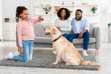 Wall Mural - Black girl training and giving treat to her obedient dog