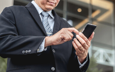 Businessman walking in city using a mobile phone while going to work.