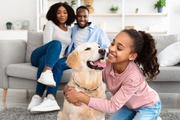 Young black girl hugging dog posing at home