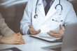 © rogerphoto - Unknown male doctor and patient woman discussing something while sitting in clinic. Best medical service in hospital, medicine, pandemic stop