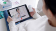 © ChayTee - Over shoulder view of young asia woman talk to doctor on cellphone videocall conference medical app in telehealth telemedicine online service hospital quarantine social distance at home concept.