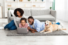 Young Black Family At Home With Laptop And Labrador