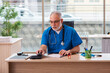 © Elnur - Old male doctor working in the clinic in telemedicine concept