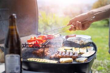 Wall Mural - BBQ on weekend. Sausages, steak, cheese and vegetables on gas grill. Outdoors.