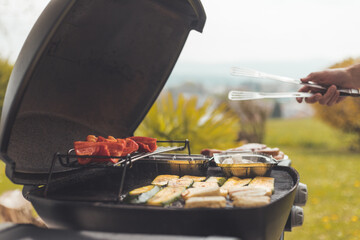 Vegetarian BBQ on weekend. Grill cheese and vegetables on gas grill. Outdoors.