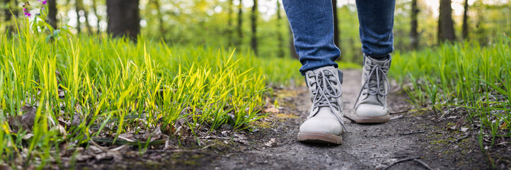 Wall Mural - hiking boot on footpath. panoramic view of hiker legs walking at woodland