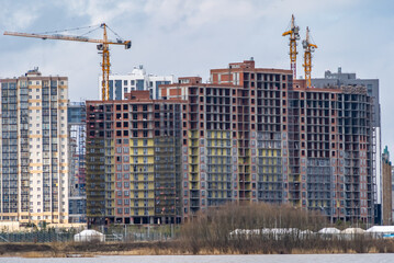 construction of monolithic apartment buildings and brickwork in a residential area of a megalopolis on the river bank