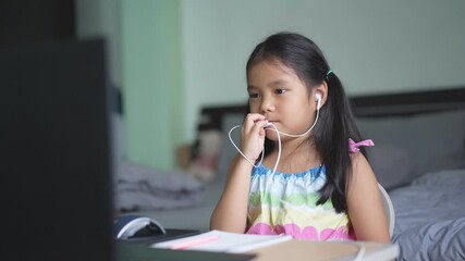 Wall Mural - Asian child or kid girl smile enjoy e-learning and speak to small talk on computer notebook with wearing headphone for study online communication or learn from home and play laptop for back to school