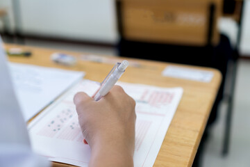 Wall Mural - Education school test concept : Hands student holding pencil for testing exams writing answer sheet or exercise for taking fill in admission exam multiple carbon paper computer at university classroom