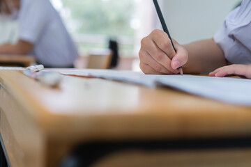 Hand female Asian students taking exam test and concentration reading document exercise at classroom in high school. Teenager notes for SAT PISA measurement educational, back to school for evaluation