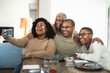 © Alessandro Biascioli - Happy black family having fun taking selfie with mobile smartphone cam while having lunch at home