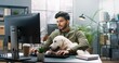 © VAKSMANV - Young handsome Hindu guy sits in office with his big Labrador Retriever dog and works on computer completing task.