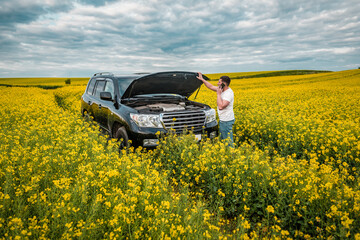 man talking on the phone near the car with the opened hood