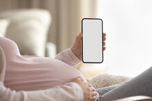 Crop Close Up Of Young Pregnant Woman Hold Modern Smartphone With Empty White Blank Mockup Screen. Female Enjoy Pregnancy Track On Cellphone Gadget Application. Technology, Motherhood Concept.