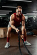 © Georgii - Sport. Strong man exercising with battle ropes at the gym with. Athlete doing battle rope workout at gym. Dramatic sports background.