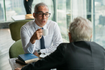 Two businessmen discussing in the corporate high-rise lounge, professional business people meeting 