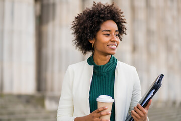 Afro businesswoman walking outdoors on the street.