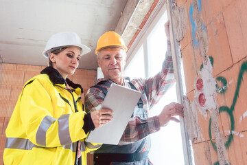 Construction worker checks a window panel wall with engineer using digital tablet