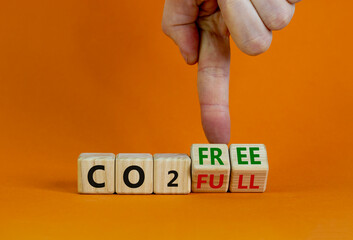 Wall Mural - CO2 full or free symbol. Businessman turns cubes, changes concept words 'CO2 full' to 'CO2 free'. Beautiful orange table, orange background. Business and CO2 full or free concept. Copy space.