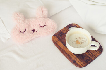 Cup of coffee with cute pink sleep mask