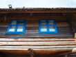 Log village farmhouse. 19th century Bosnian mountain traditional dwelling. Restored ethno building, Two windows with blue frames.