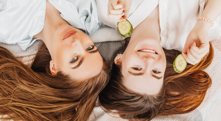 Wall Mural - two girls make homemade face and hair beauty masks. cucumbers for the freshness of the skin around t
