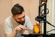 © phoenix021 - Man removing, scraping,  extra plastic parts from 3d printed object