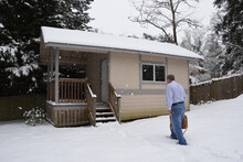A Man Walking In The Snow To The Detached Home Office In The Backyard.