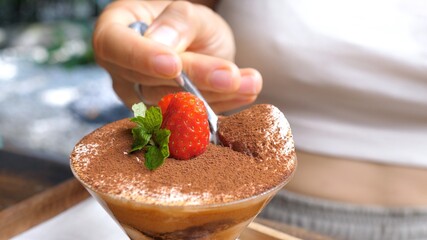 Close up of a spoon taking a piece of dairy free tiramisu decorated with strawberry. Classic Italian desserts in vegan option