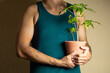 © Narayan - man holding a potted tree for decoration, houseplant concept
