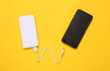 canvas print picture - Smartphone and External portable battery (power bank) on yellow background. Top view. Flat lay