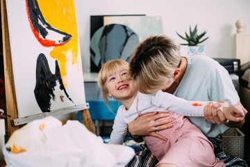 Wall Mural - beautiful mother artist and her child paint picture at home with acrylic paints.